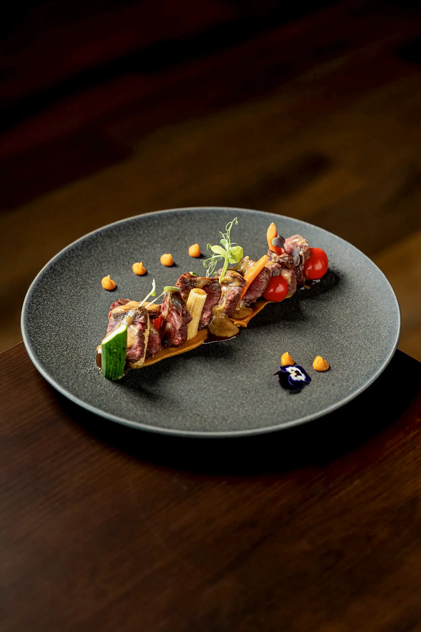 Carne en brocheta con verduras, sobre plato gris