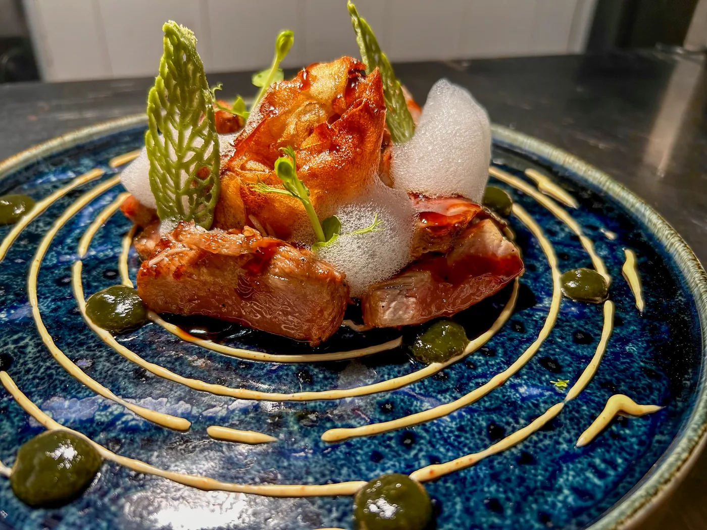 Pescado con teja crujiente sobre un plato azul en espiral